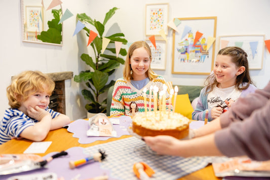 Children enjoying a craft birthday party with peg doll craft kits laid on the table