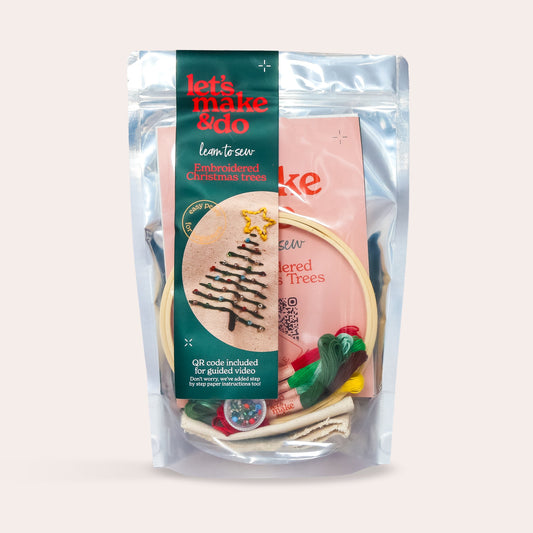 Packaged learn to sew hand embroidery craft kit with Christmas tree design on a light beige background